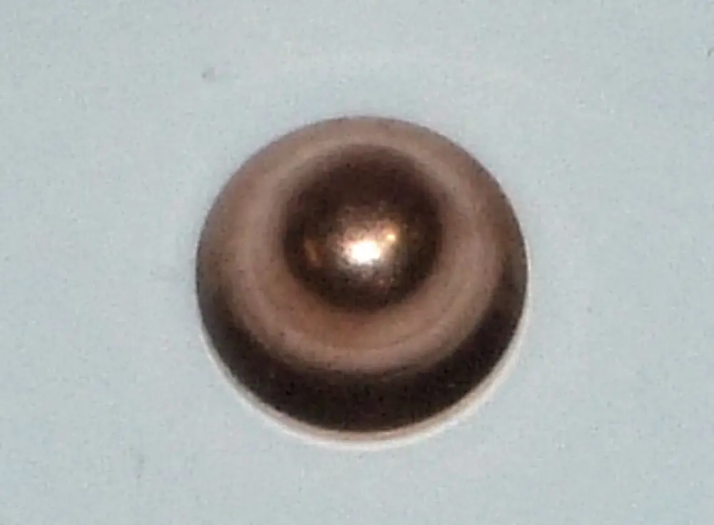 Runde Schraubenmutter aus Metall, möglicherweise von Daikin, mit glatter Oberfläche und gewölbtem Zentrum, auf einem hellen Hintergrund.